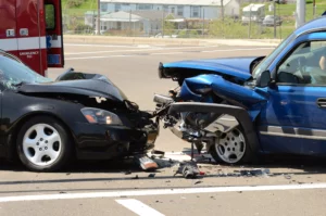 A Black Sedan And A Blue Suv Are Shown With Severe Front-End Damage After A Head-On Collision At An Intersection, Emphasizing The Seriousness Of These Crashes And The Need For An Experienced Arlington Head On Collision Lawyer To Pursue Justice For Injured Victims.