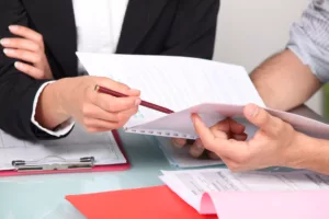 Two Individuals Reviewing Paperwork Together At A Desk, Illustrating The Concept Of What Is Discovery In Law.